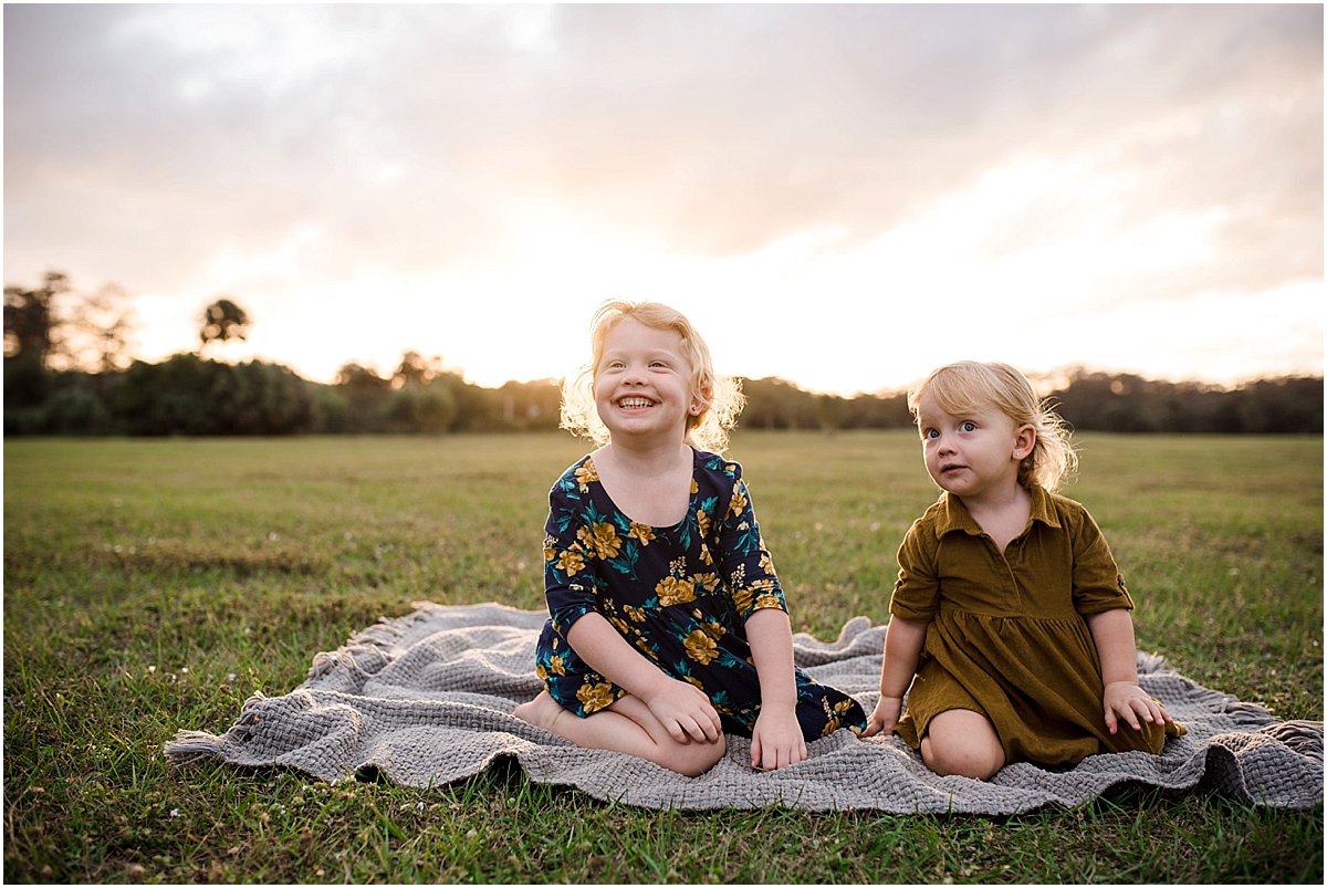 sisters laughing in a field | Orlando Lifestyle Newborn Photographer