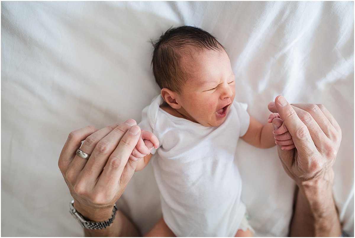 newborn baby boy yawning while grasping daddy's fingers | orlando newborn photographer