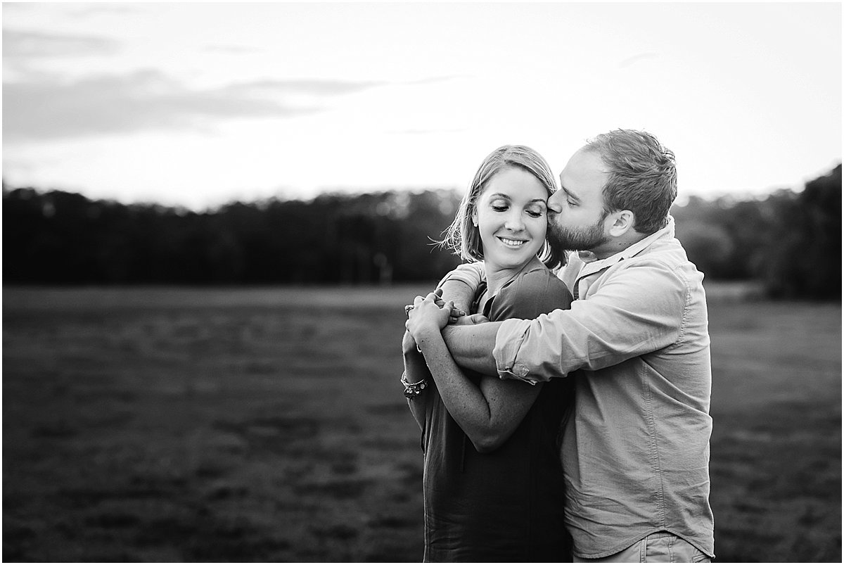  mom and dad hugging in a field during family photos 