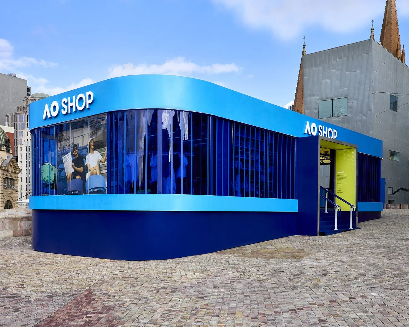 A modern storefront with blue exterior and glass windows displaying mannequins, labeled 'AO SHOP'.