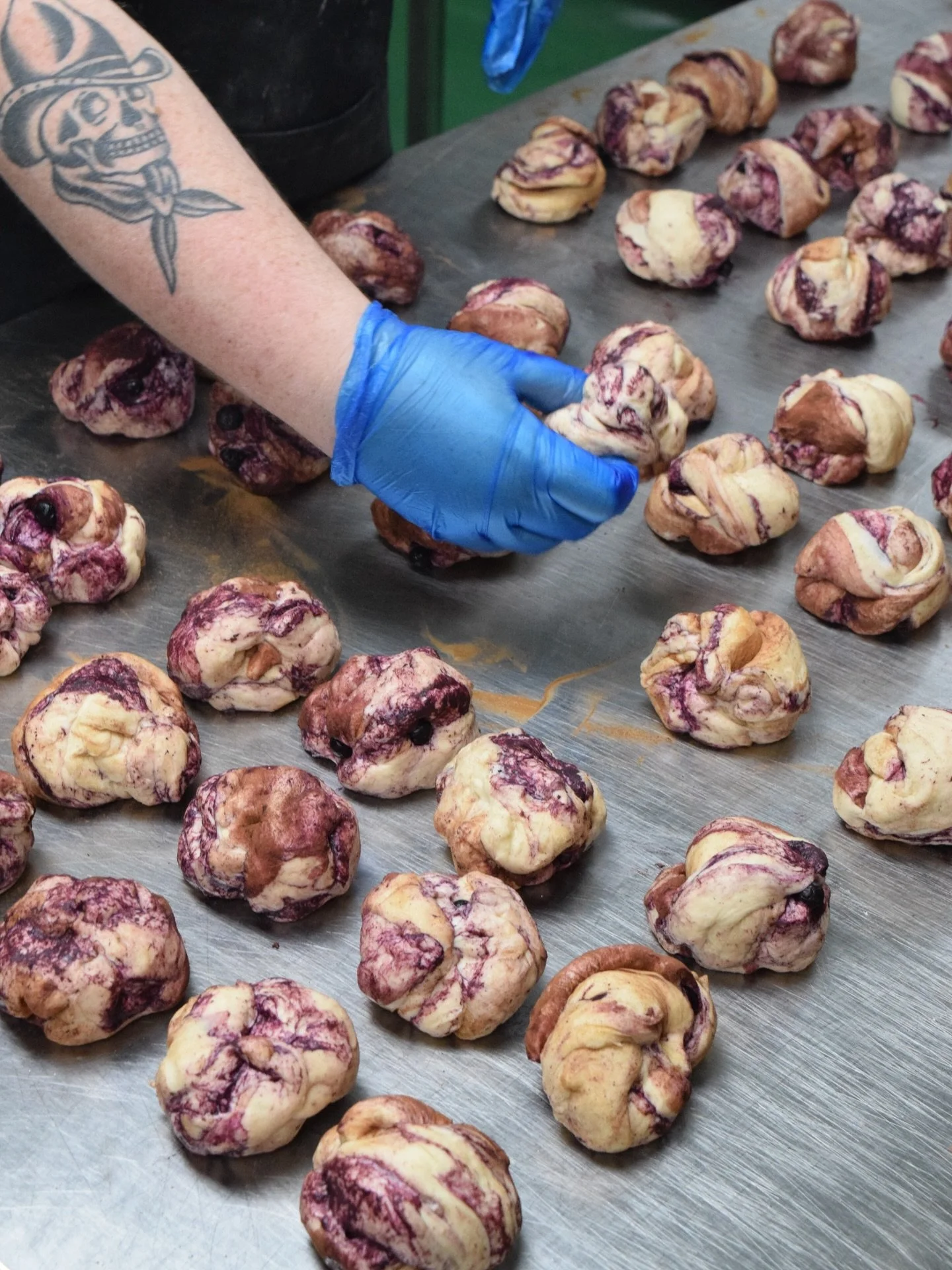 This is what handmade looks like at scale.
Blueberry folded through the dough, shaped by hand, spaced out to breathe.
No shortcuts. Just a lot of trays.
