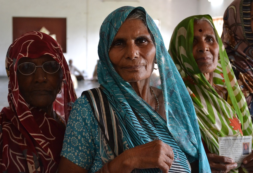 Ladies enrolled in the poverty alleviation programme queue up to receive a solar lantern, ID cards in hand.