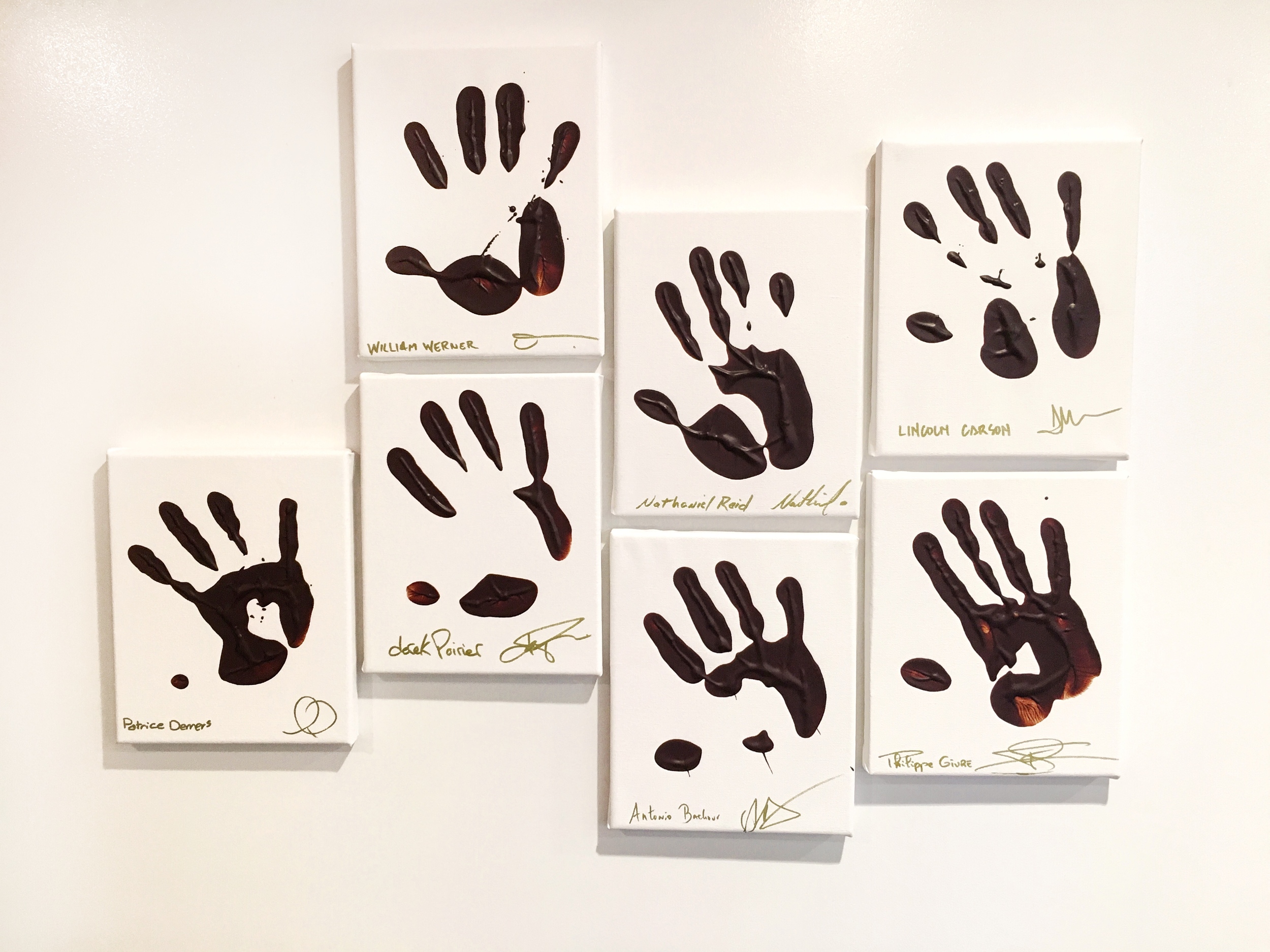 Famous chefs like Lincoln Carson with their hands dipped in chocolate, on the wall at Valrhona in Brooklyn