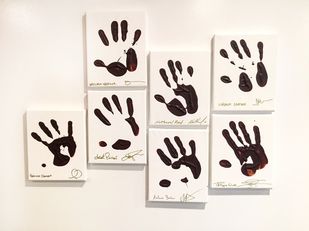 Famous chefs like Lincoln Carson with their hands dipped in chocolate, on the wall at Valrhona in Brooklyn