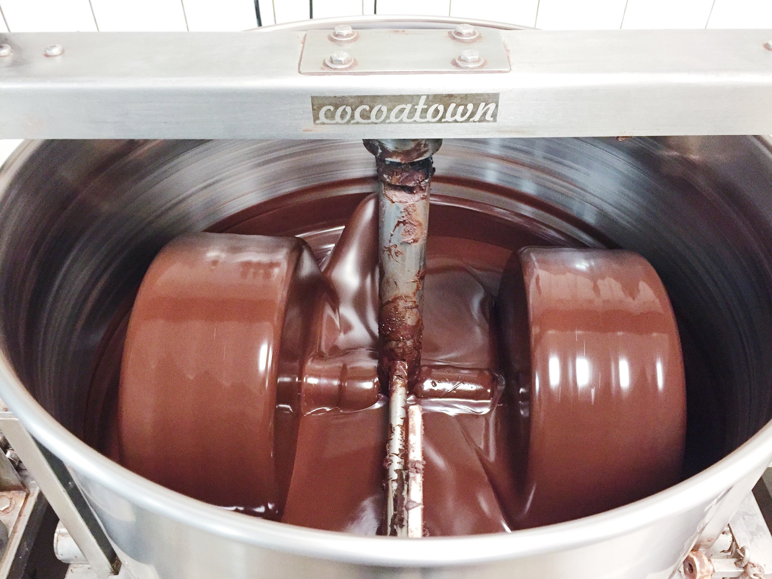 I pretty much visit Raaka Chocolate ' s factory once a week. The first thing you see when you walk in the door is their tasting room, with tons of chocolate samples. But the best thing is watching the Cocoatown machines grind and refine cocoa nibs into chocolate. Sometimes they let me taste a spoonful straight out of the machine. This batch is their limited-edition strawberry basil flavor. 
