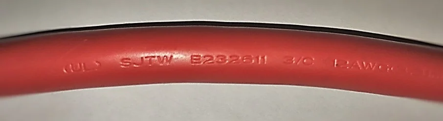 Close-up of an extension cord designed for hard usage "SJTW" commonly found on construction sites.