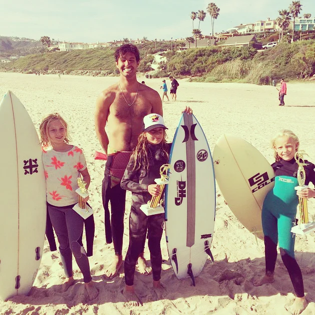 Kili Garrett with her 4th place trophy, Hannah Dunfee with her 3rd place trophy, and Sierra Downer with her 2nd place trophy along side their coach and founder of Crook's Surf Essentials, Collin Crook!