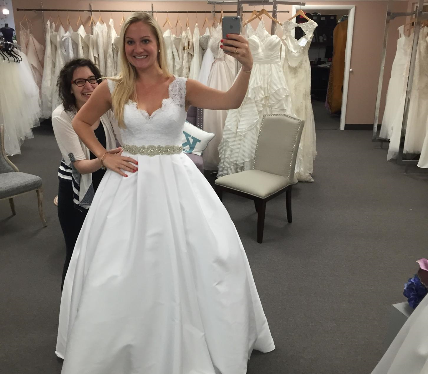 Bride-to-be trying on a dress with the help of a bridal consultant