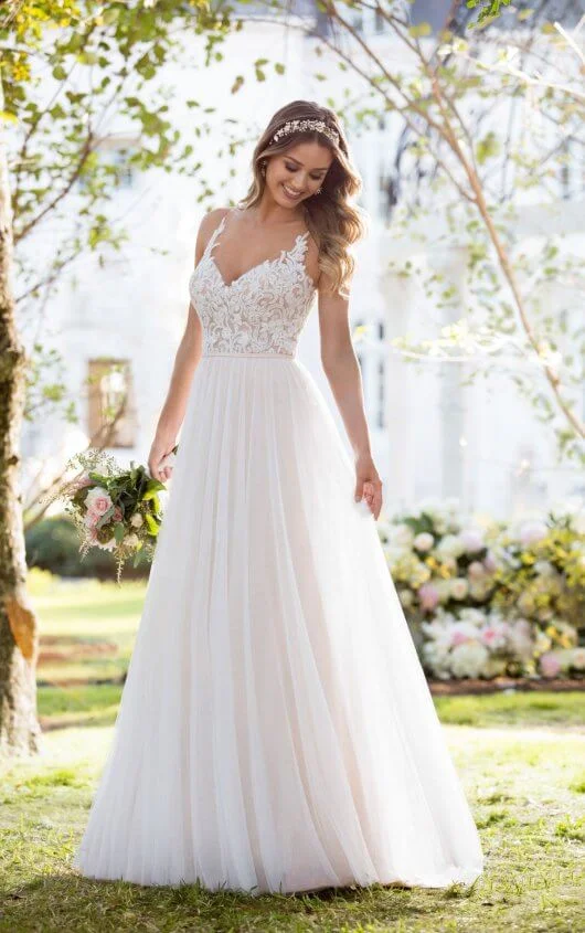 6555 - Soft, romantic, and light-as-air, this boho wedding dress from Stella York was made for the laidback, casually-cool bride. The bodice of this French tulle over matte-side Lavish satin gown is constructed of double organza, giving the appearance of sheerness. Adorned with lace swirls and beading, it is the perfect complement to the tulle, A-line skirt. The back of this gown features an intricately-detailed illusion-tulle design, and a slight train, making it perfect for a boho-inspired celebration. This boho wedding dress zips up beneath pearl buttons. Colors Available - All Ivory, Ivory/Moscato/Mink, All White 