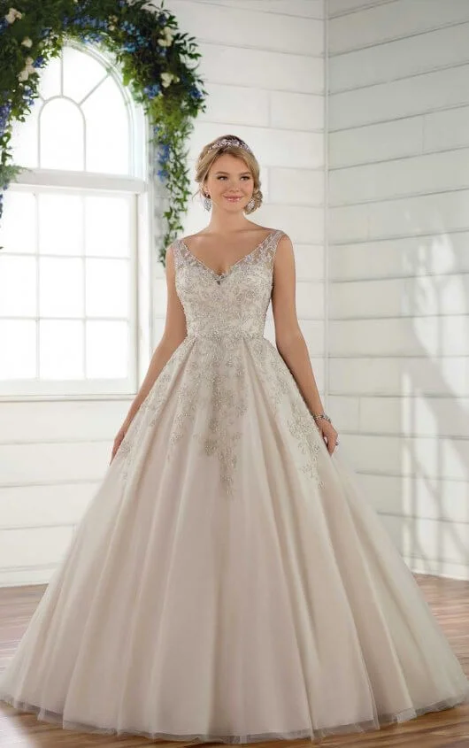 D2499 - Make a statement on your wedding day in this dramatic ballgown from Essense of Australia! Beaded lace adorns the bodice of this gown, adding the perfect amount of sparkle to an already-breathtaking style. A V-neckline highlights your face effortlessly and is balanced out with a full ballgown skirt, complete with beaded lace detailing around the waist. A sheer V-back highlights the back of this ballgown and is complemented with beaded lace that adorns the back of the skirt and edge of the train, creating a dramatic element as you walk down the aisle. The back of this glamorous ballgown zips up beneath fabric-covered buttons and is available in plus sizes Colors Available - White/Silver, Ivory/Silver, Ivory/Almond/Moscato/Silver