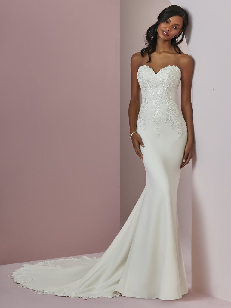 Billie - This Aldora Crepe fit-and-flare wedding gown features embroidered lace motifs along the bodice, strapless sweetheart neckline, and back hemline. Subtle illusion accented in lace motifs completes the scoop back. Finished with crystal buttons and zipper closure. Available in - Soft Pearl