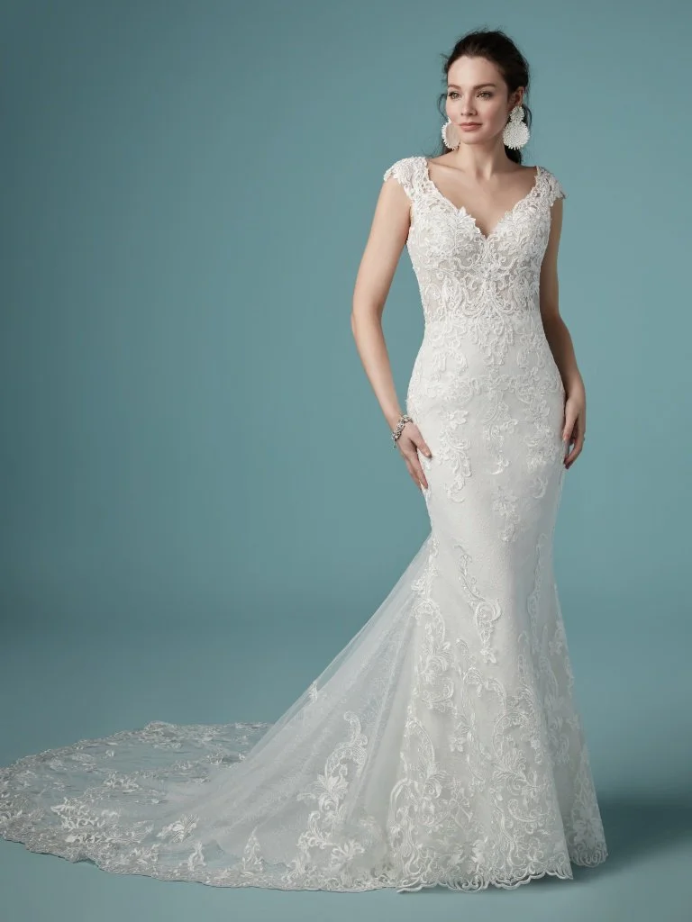 Celeste - Beaded embroidered lace motifs cascade over Chantilly lace in this soft sheath wedding dress, accenting the illusion double-lace train. The bodice features a delicate V-neckline, sheer cap-sleeves and scoop back, all accented in beaded lace motifs. Finished with covered buttons over zipper closure. Available in plus size. Available in: Ivory/Nude, Ivory/Soft Blush