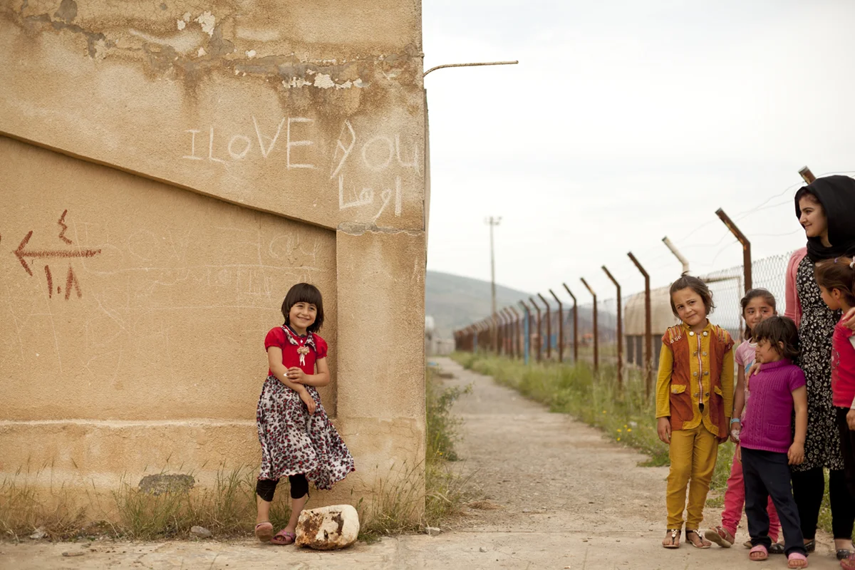 Yazidi refugee children and their beloved Kurdish school teacher outside at a abandoned soccer stadium near a refugee camp in Iraqi Kurdistan (May 2016).