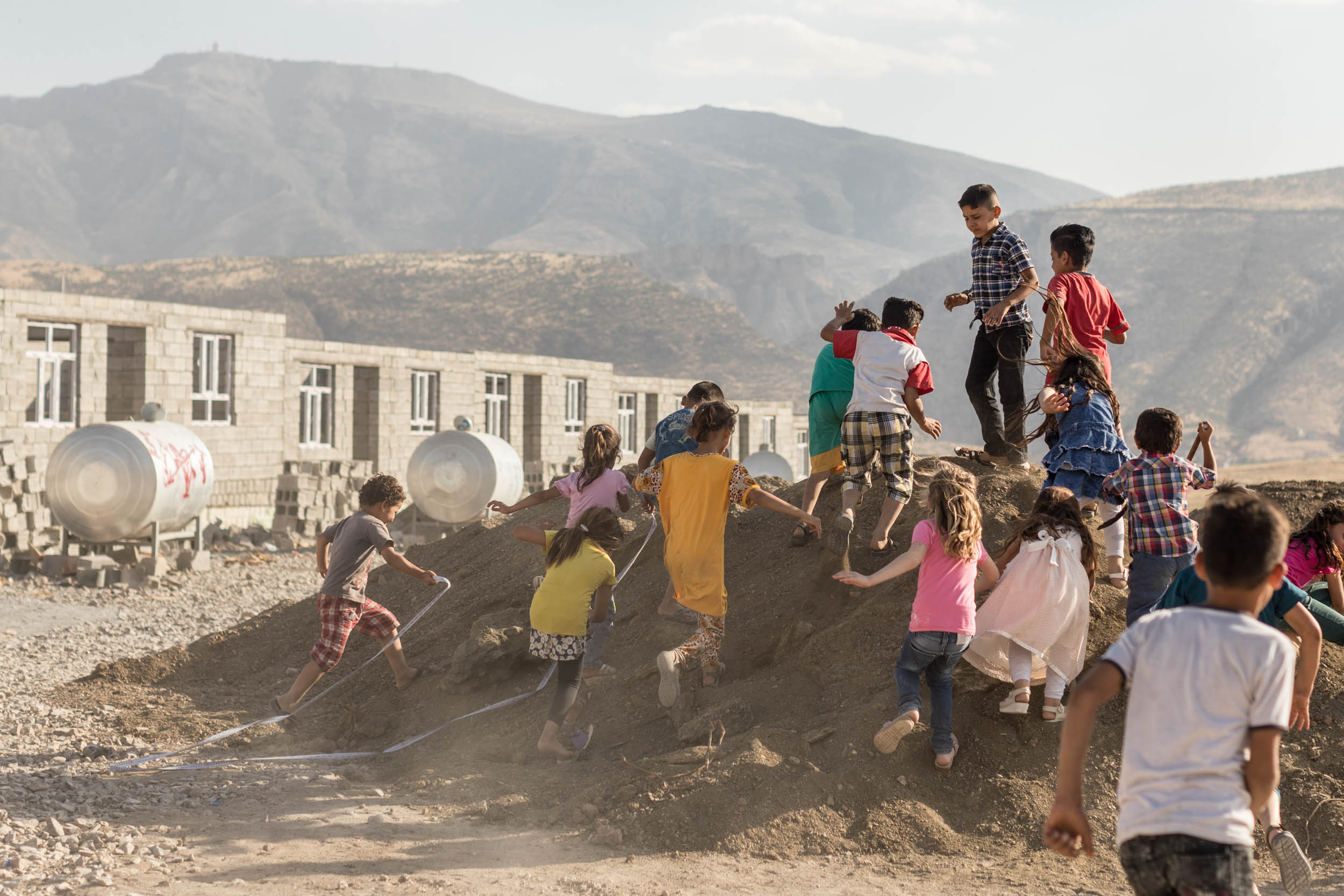  Yazidi children play at the construction site of a neighboring camp being built for newly arriving Syrians to Soran, Iraq (2017).  