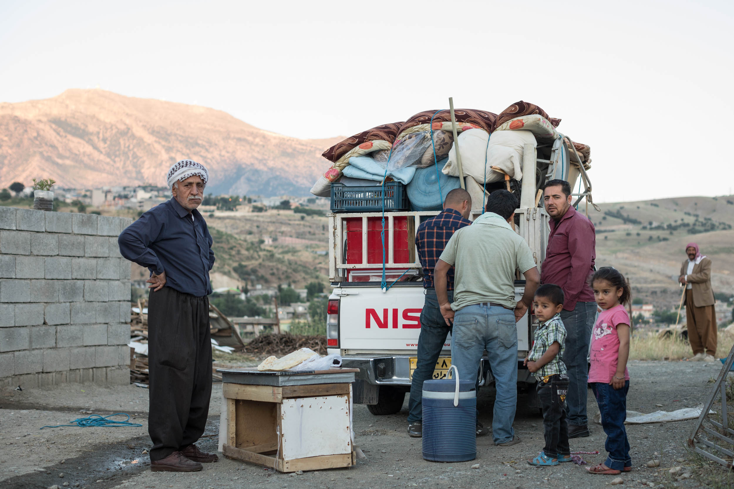  Mosul family packing their belonging to return home while neighboring Yazidi friends watch (2017). 