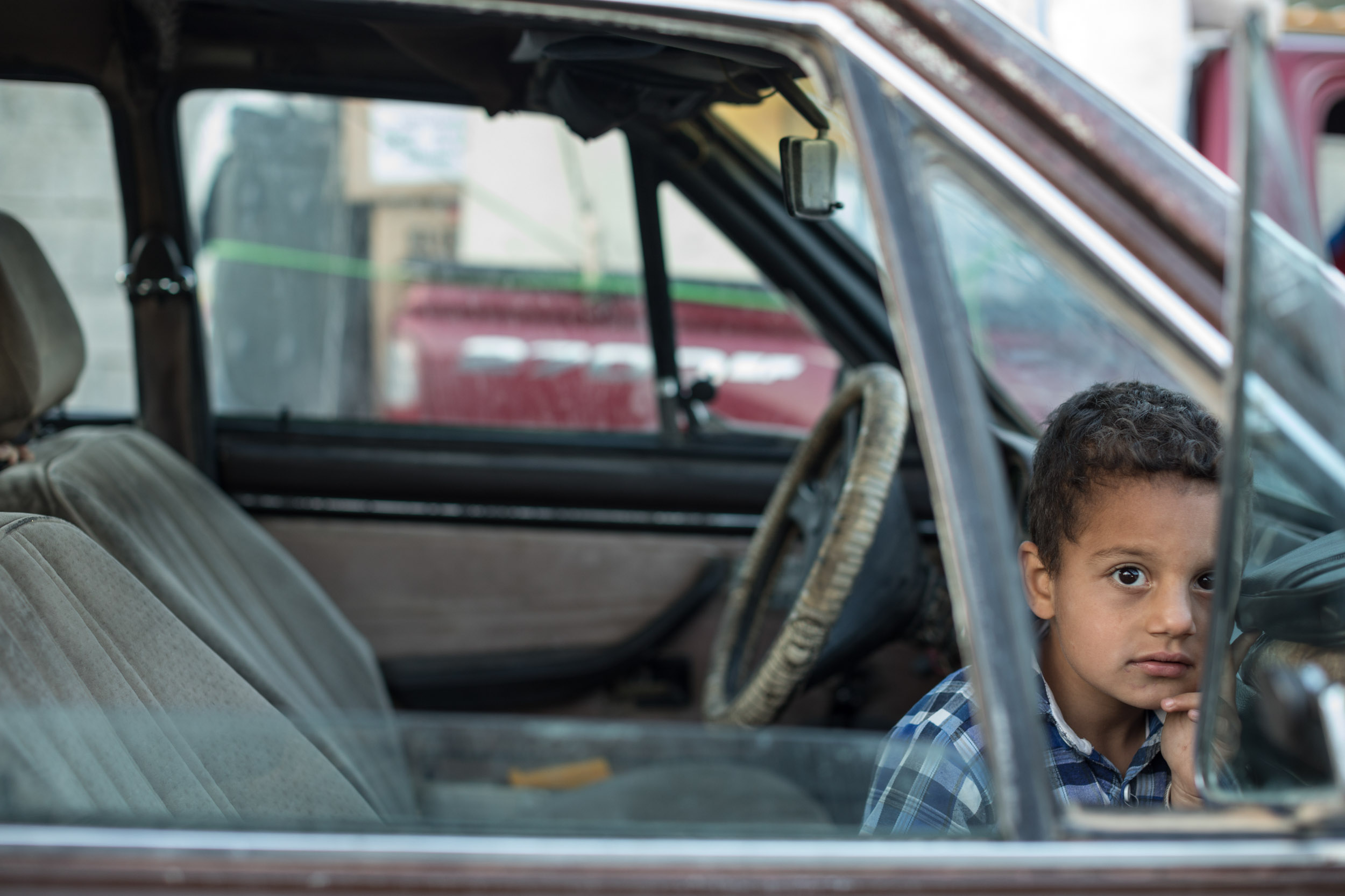  Boy from Mosul, Iraq waits in the car to return home as his parents pack up the shelter they lived in for three years after fleeing ISIS in 2014 (May 2017). 