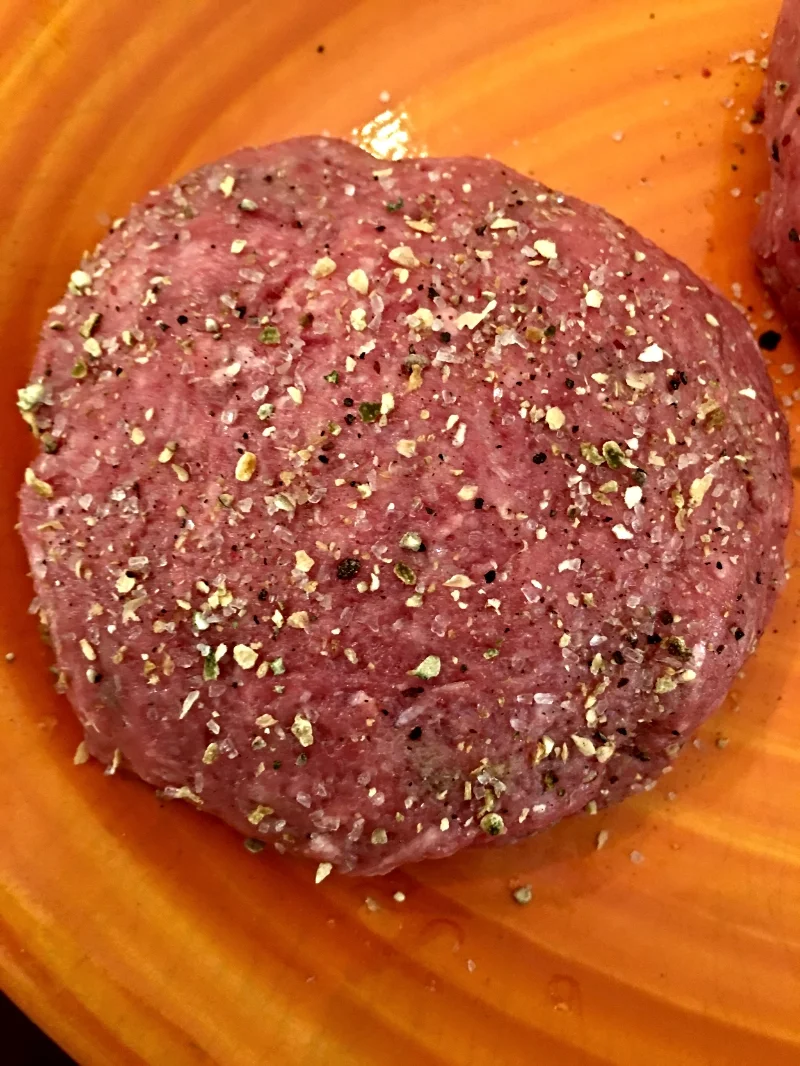 Close-up of seasoned burger patty