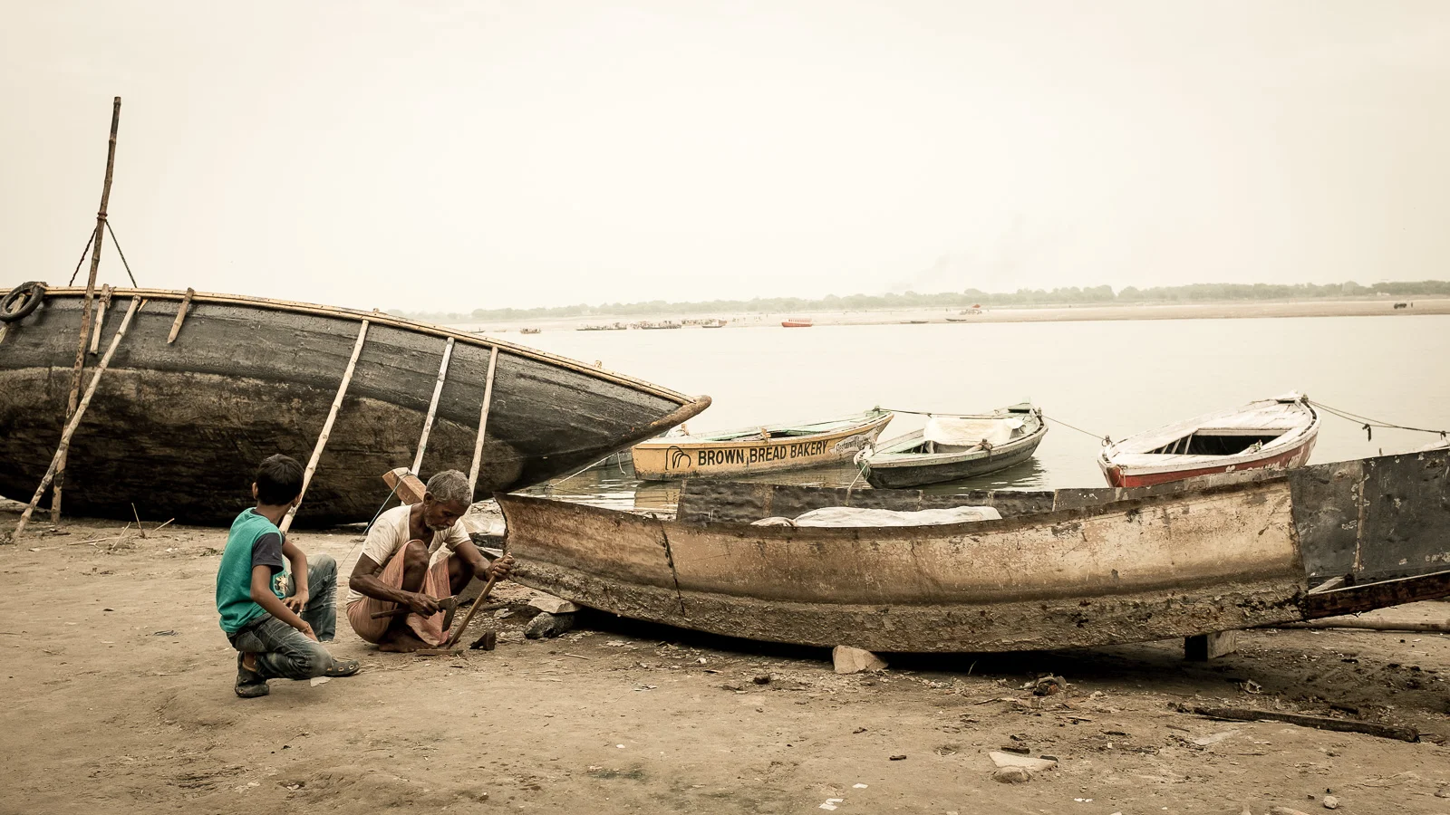 A grandad and nephew are working on a boat. Varanasi, Uttar Pradesh.