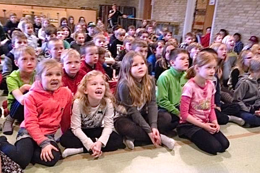 Fra storskærmen i salen kunne eleverne fra 1. til 4. klasse synge med til live-optagelserne på DR Ultra. Foto: Blovstrød Skole