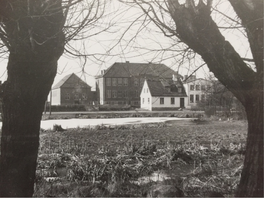 På billedet ses den gamle skole. Det er den hvide, stråtækte bygning, med den nye, store skole bagved. Fotoet er udlånt af LAFAK.