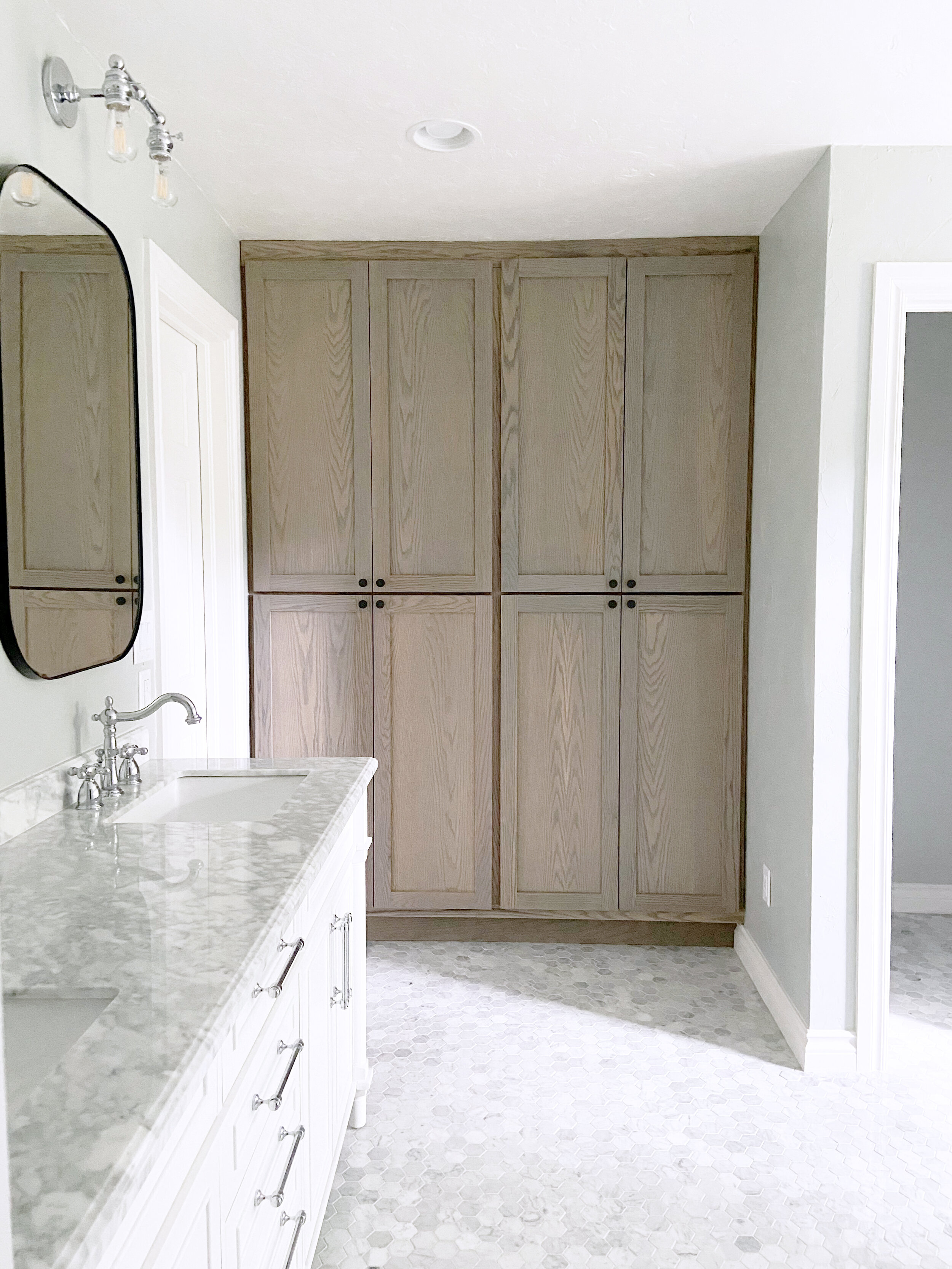 white vanity with marble top and stained oak storage cabinets.jpg