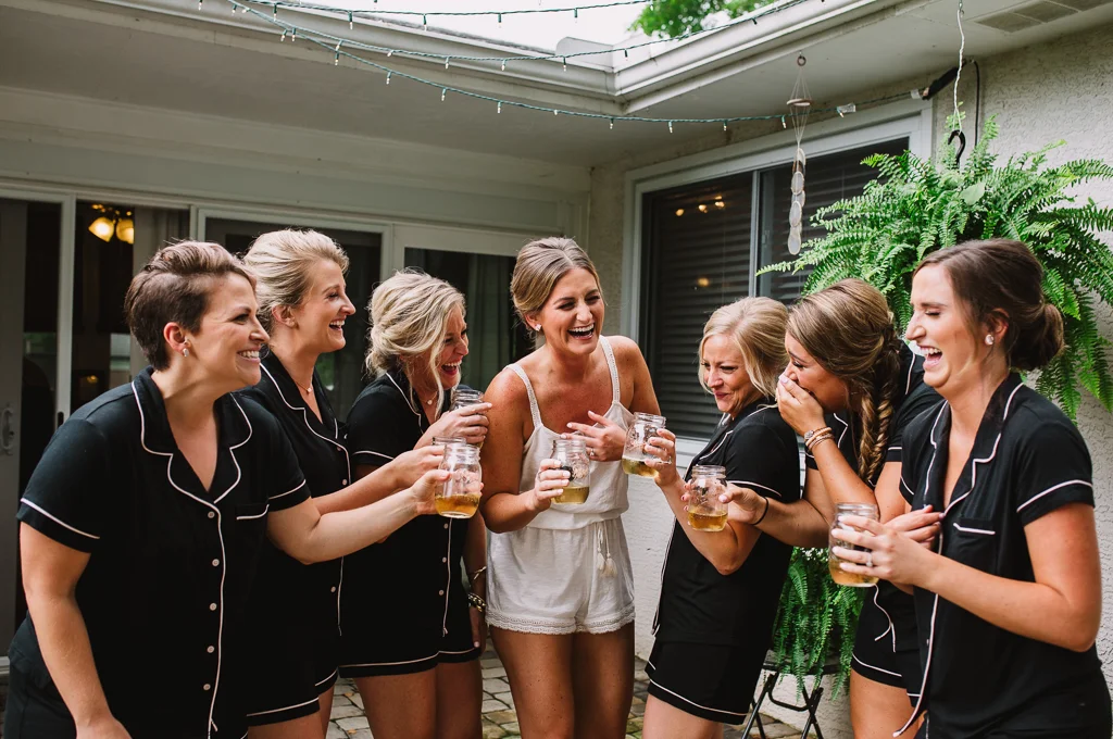 Bride and bridesmaids in matching pajamas laughing hysterically while getting ready for the wedding at Strongwater.