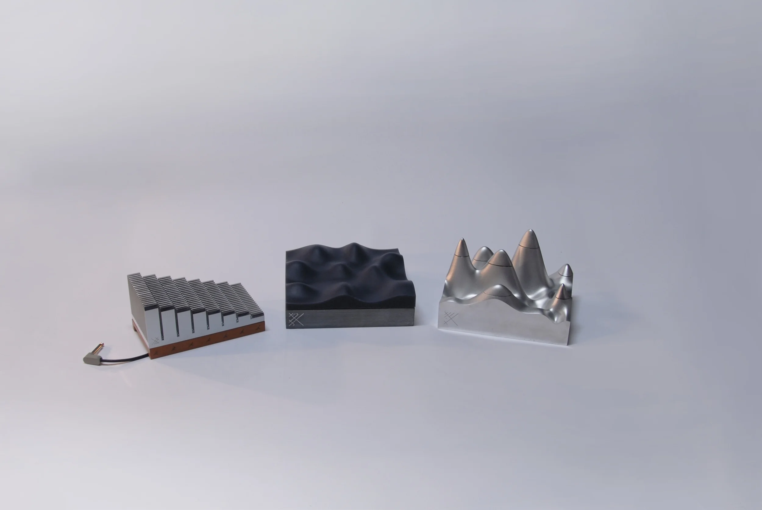 The three products on offer are the result of an exploration into musical systems design. The impetus for applying industrial design principles to the music sector was to de-clutter the systems associated with composition and performance. This would thereby contribute to shallowing the immense difficulty curve prospective students face when being introduced to music theory for the first time. After basic and applied research it became apparent that a new codified system for music theory could not possibly be universal - sound after all, is a fluid and perceptually ambiguous medium. In the wake of this conclusion a new direction was formed. A direction that dictates the creation of physical instruments or tools to aid musicians in the traversal of the sensory landscape, through sensorial interaction rather than semantic construction. The practical outcome of which is a series of new musical instruments that emphasise nuanced and progressive interaction, free exploration and, a focus on sculptural yet practical form and material treatment. These guidelines push against the current market by making the importance of emotional connections between instrument and performer a priority.