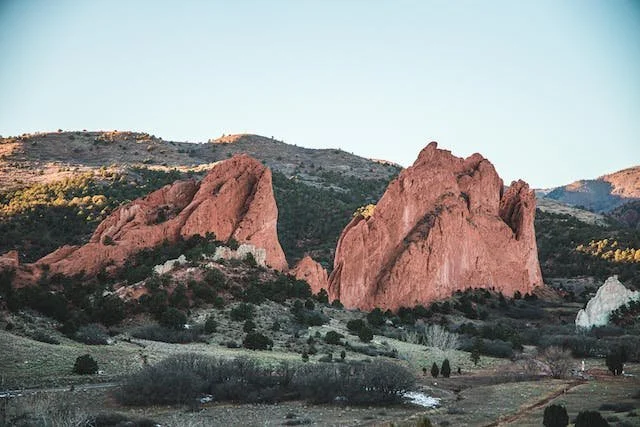 Red rocks formation in a mountainous landscape with sparse vegetation and a clear sky