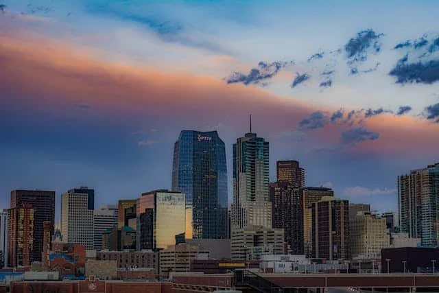 City skyline at sunset with tall buildings and a colorful sky with clouds