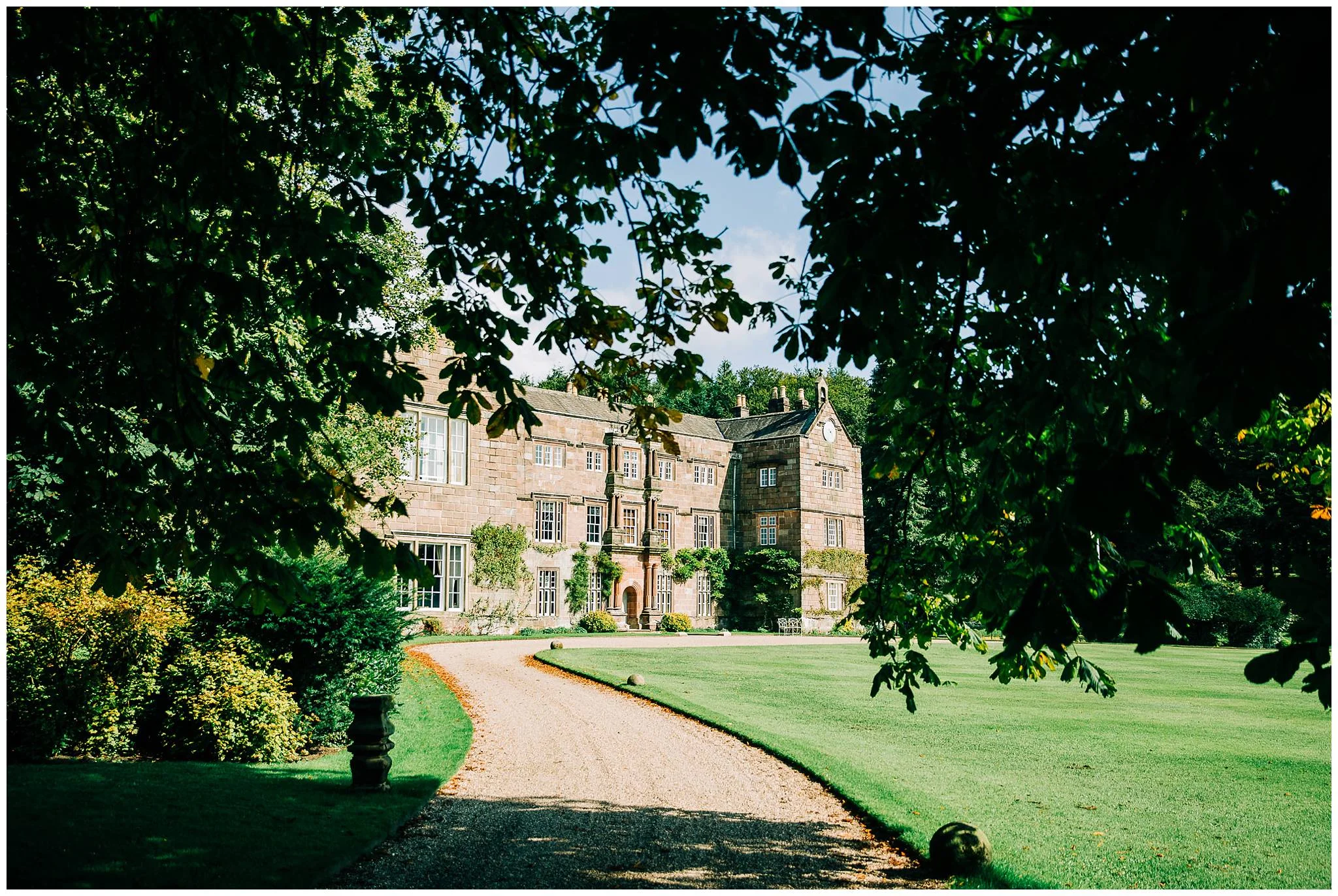 A shaded leafy canopy is framing Browsholme hall which is in the sunny background