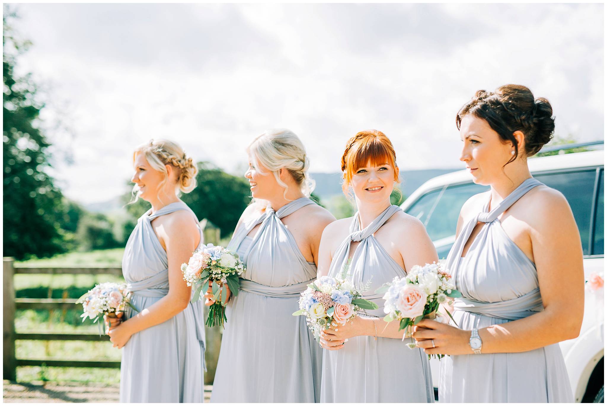 the 4 bridesmaids are stood by a car holding their bouquets and are waiting for the brides arrival