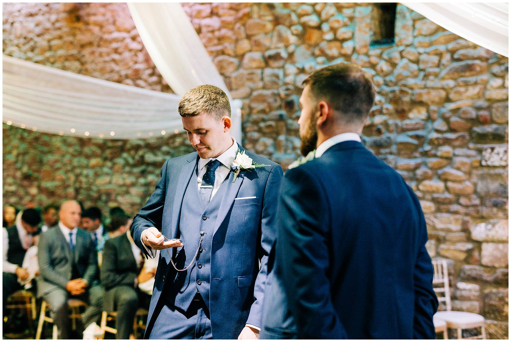 groom looks nervous as he looks down at his pocket watch in his hand