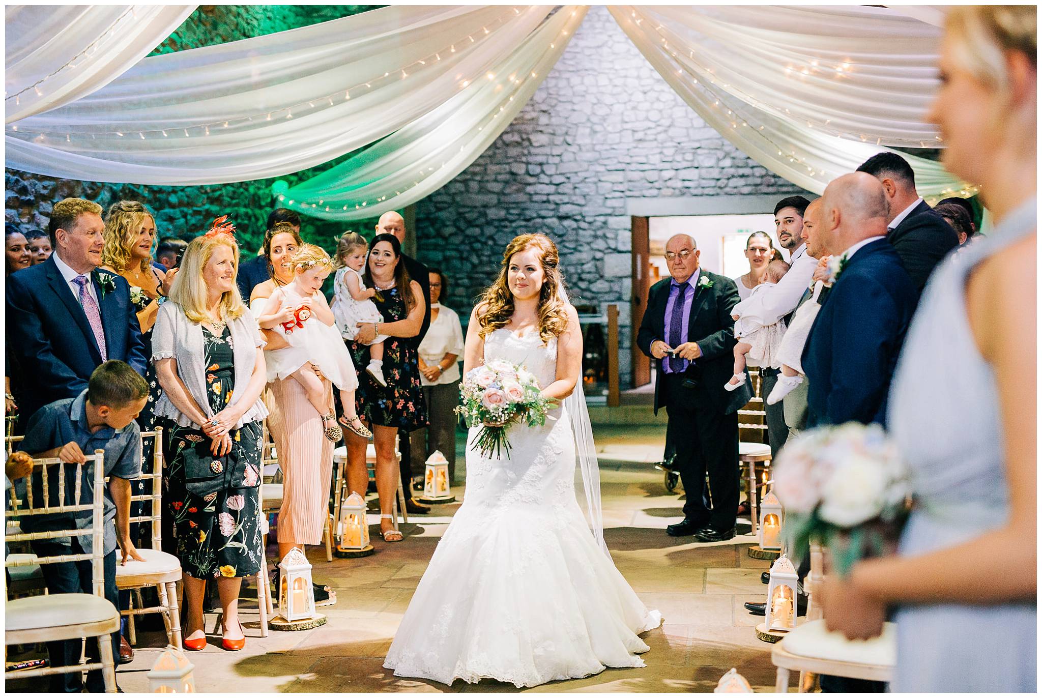 bride walks down the aisle on her own full of smiles at browsholme hall tithe barn