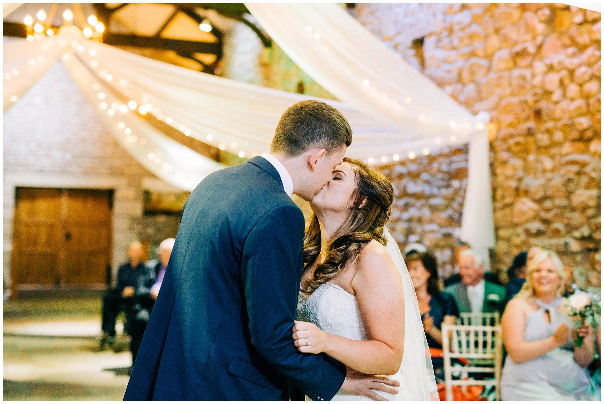 bride and grooms first kiss as mr and mrs at rustic barn venue browsholme hall tithe barn