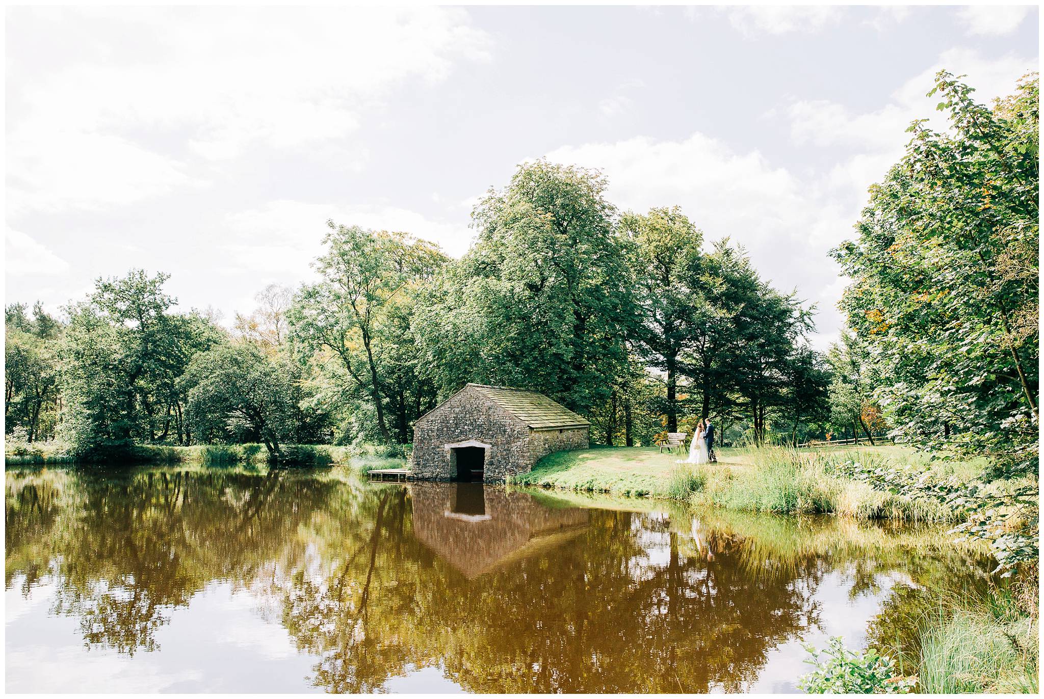 bride and groom featuring wuite small in a landscape image of the large lake at browsholme hall tithe barn