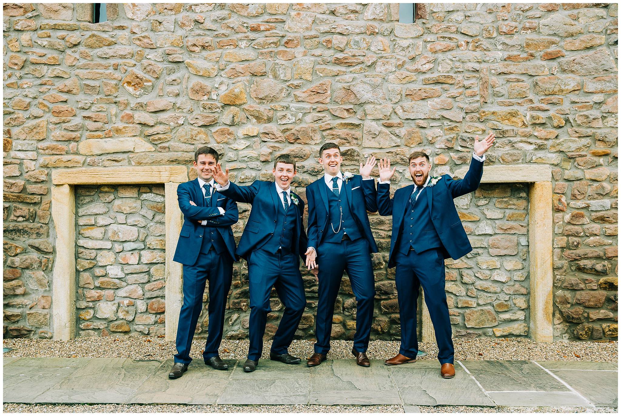groom and groomsmen being silly tithe barn stone wall from the browsholme hall estate