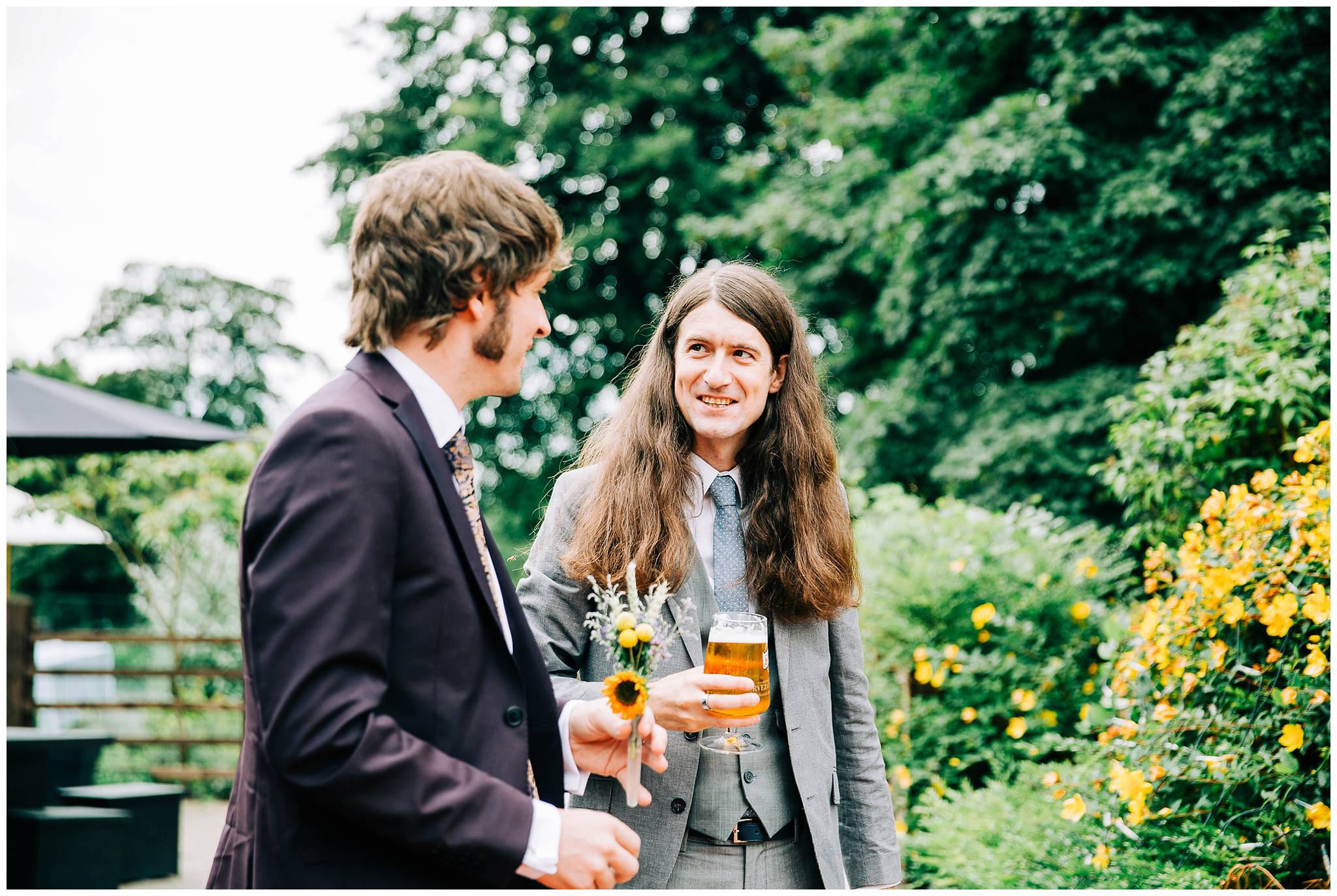 groom talking to smiling guests with long hair holding a beer