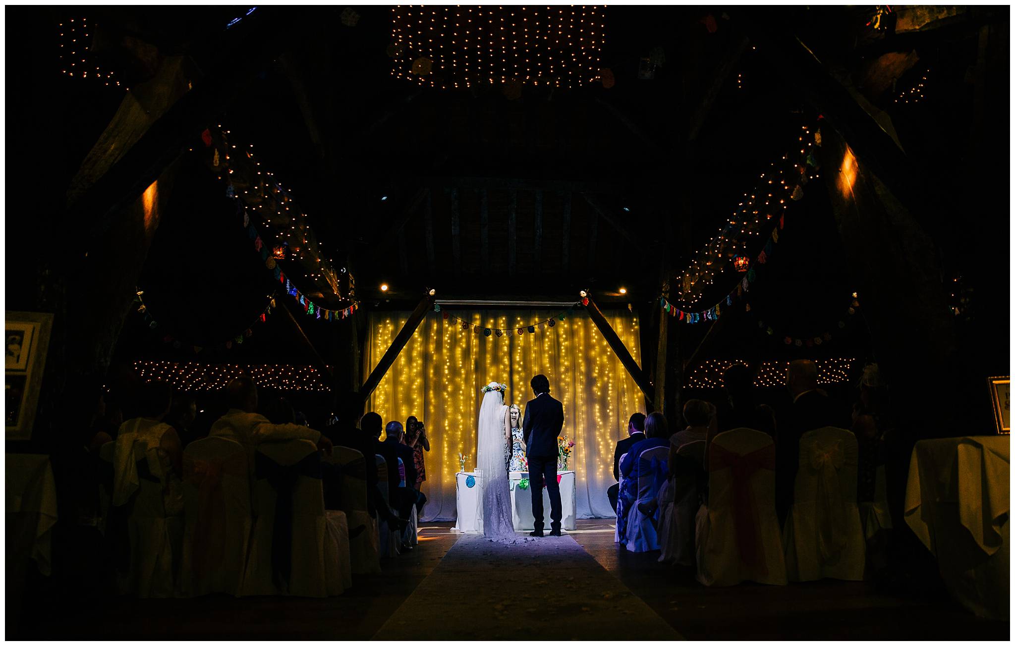 bride and groom stood in aisle lit up by a spot light