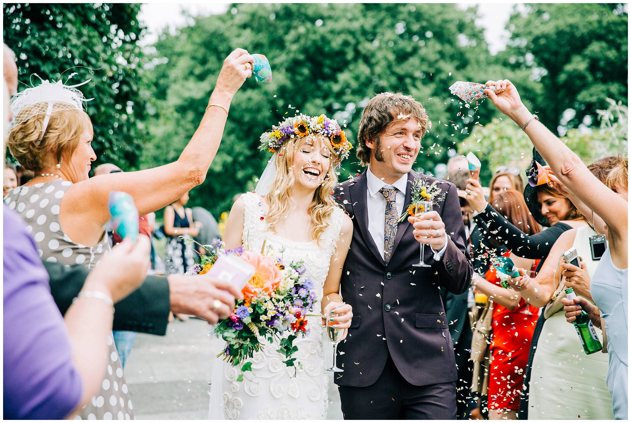 bride and groom laughing whilst getting a face full of confetti