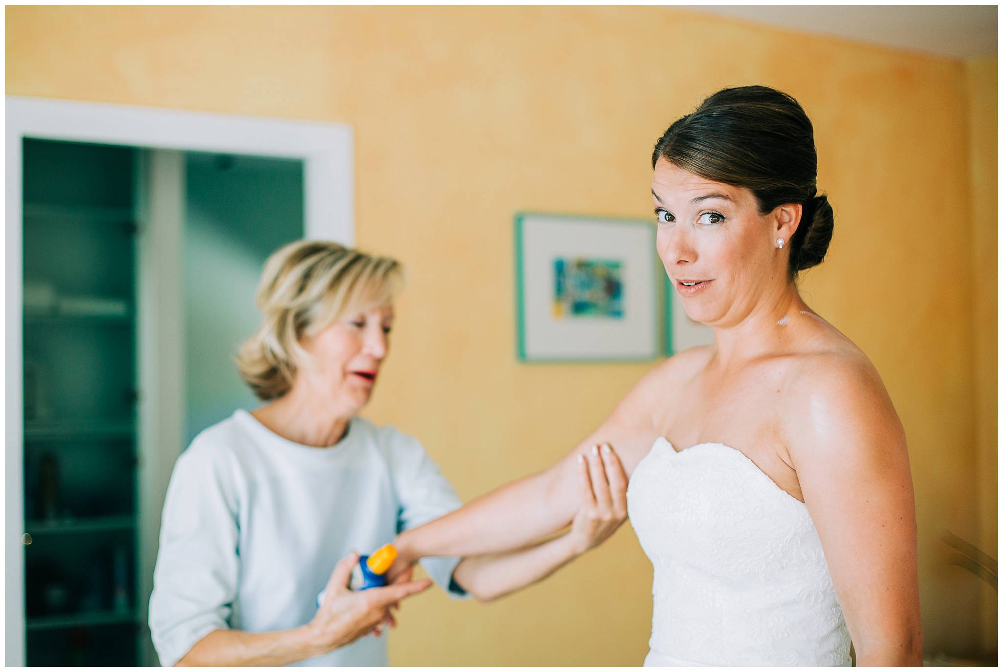 the bride having sun cream applied by her mother for her outdoor vineyard wedding