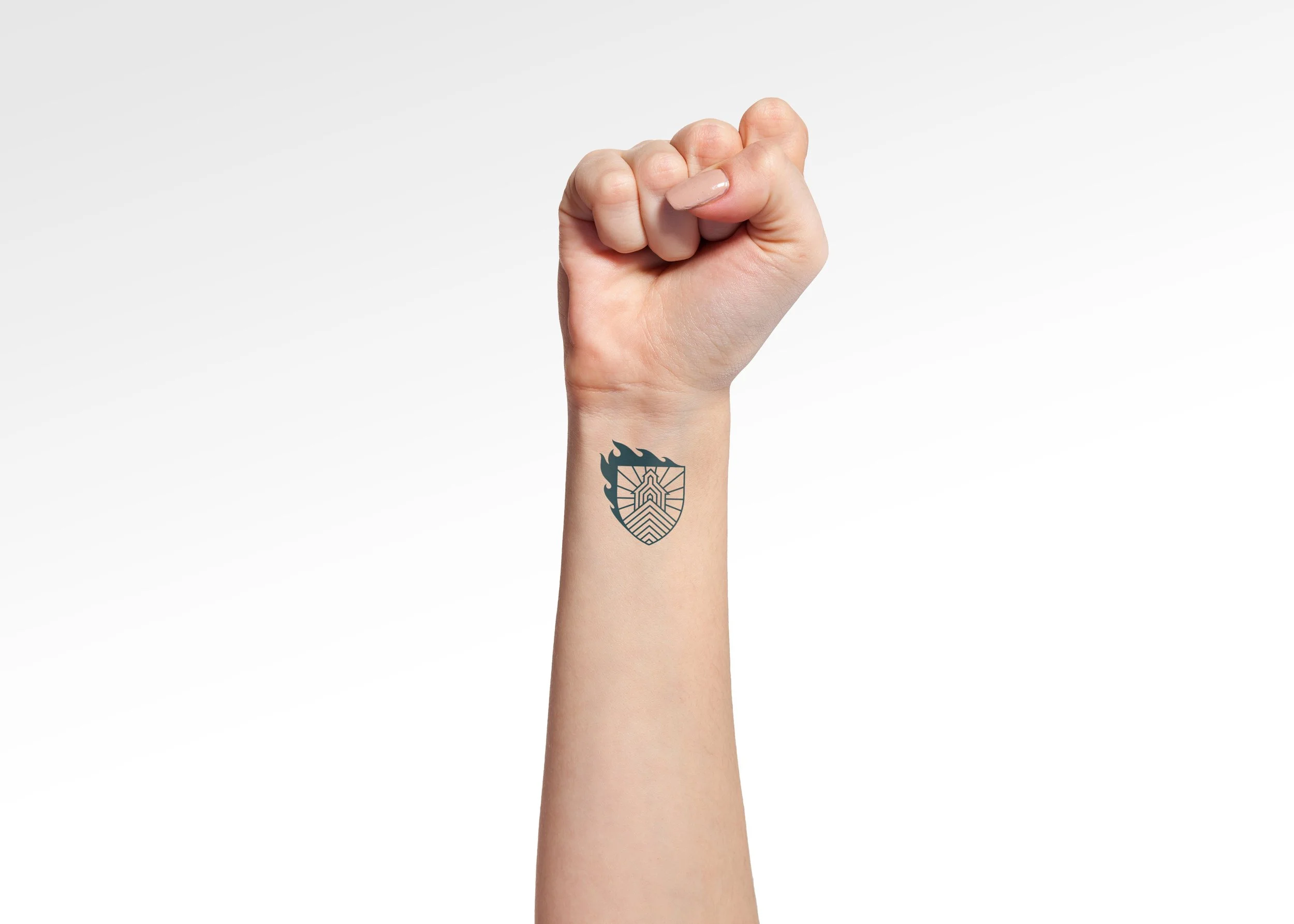 A fist raised in revolution with a tattoo of the Chefs in Schools emblem on the wrist.