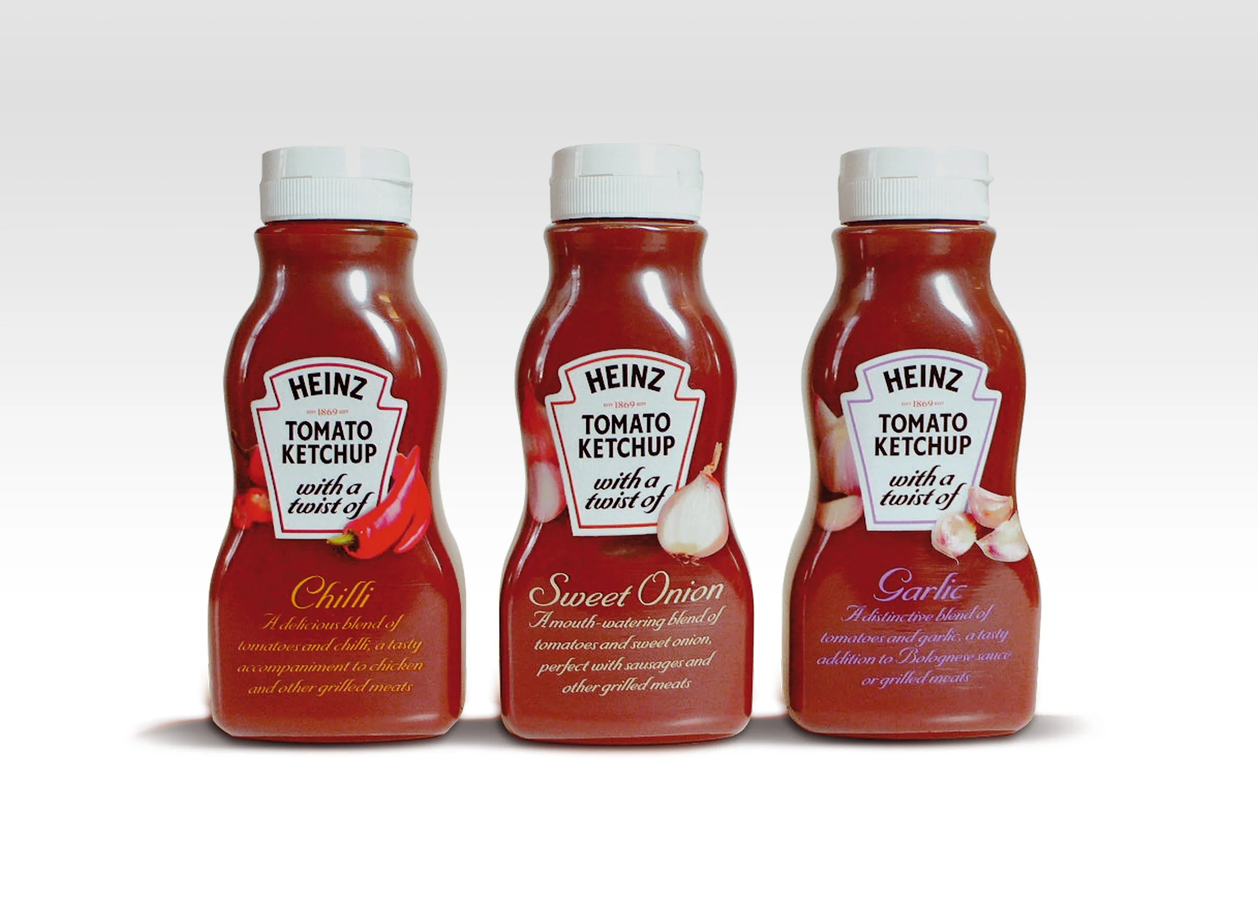 Three bottles of Heinz ketchup with different flavored labels: Chilli, Sweet Onion, and Garlic, standing side by side on a white background.