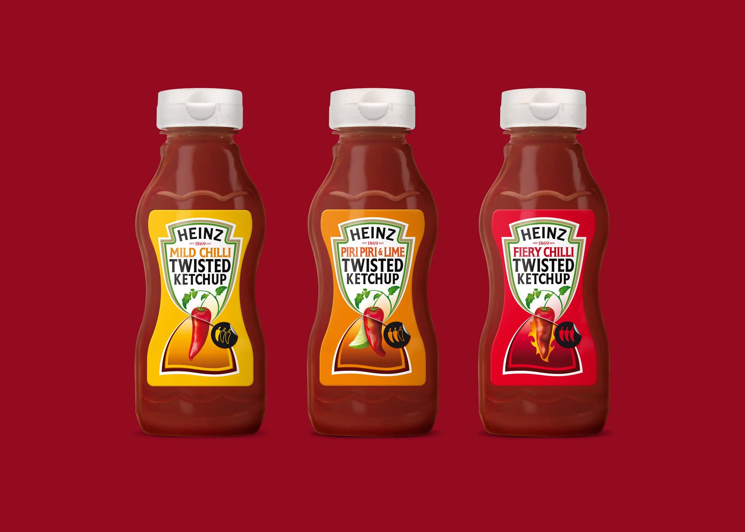 Three Heinz Twisted Ketchup bottles with different chili flavors: Mild Chilli, Piri Piri & Lime, and Fiery Chilli, standing on a red background.