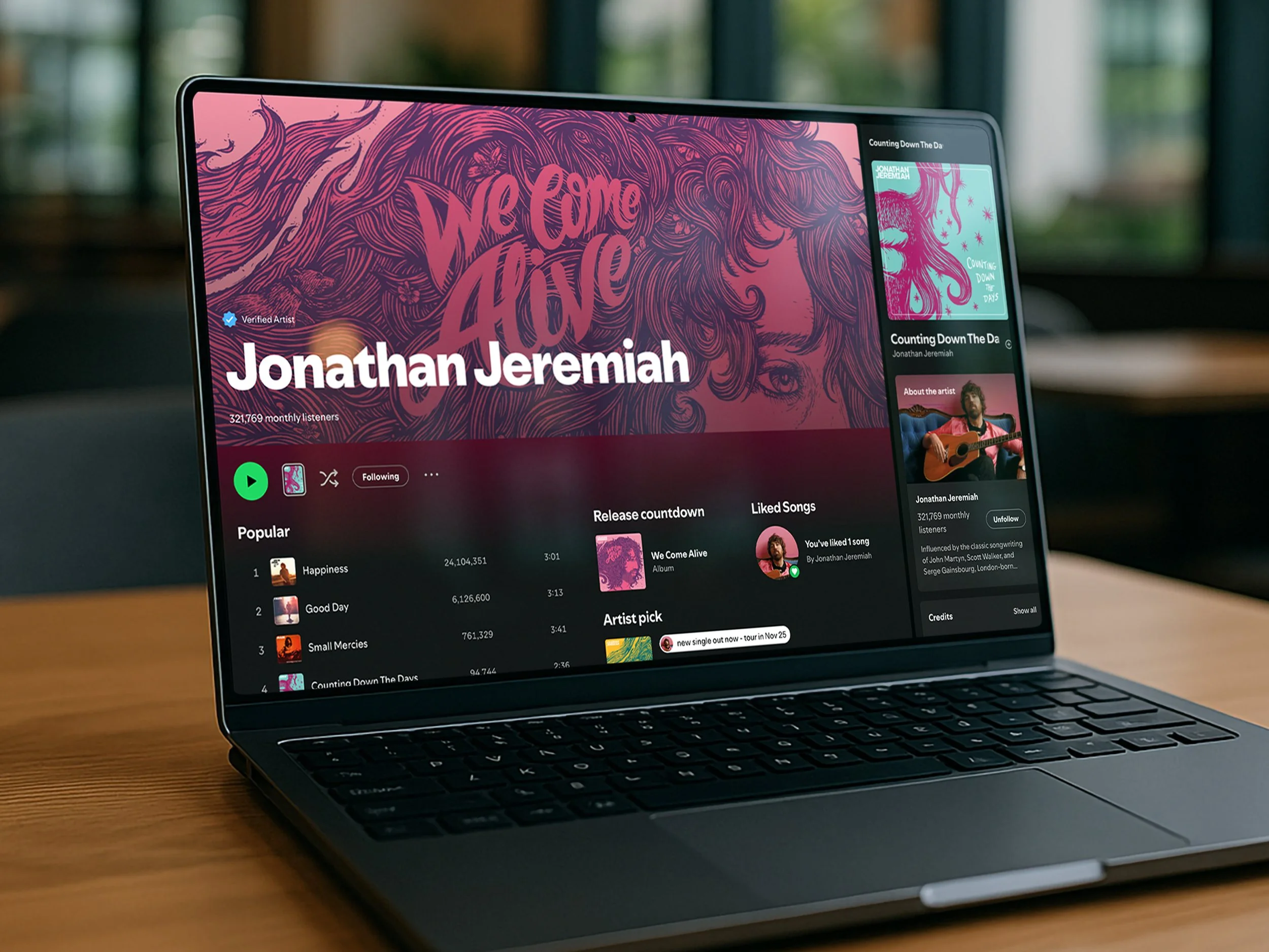 Laptop displaying a music streaming app profile of artist Jonathan Jeremiah with album art, song list, and artist information.
