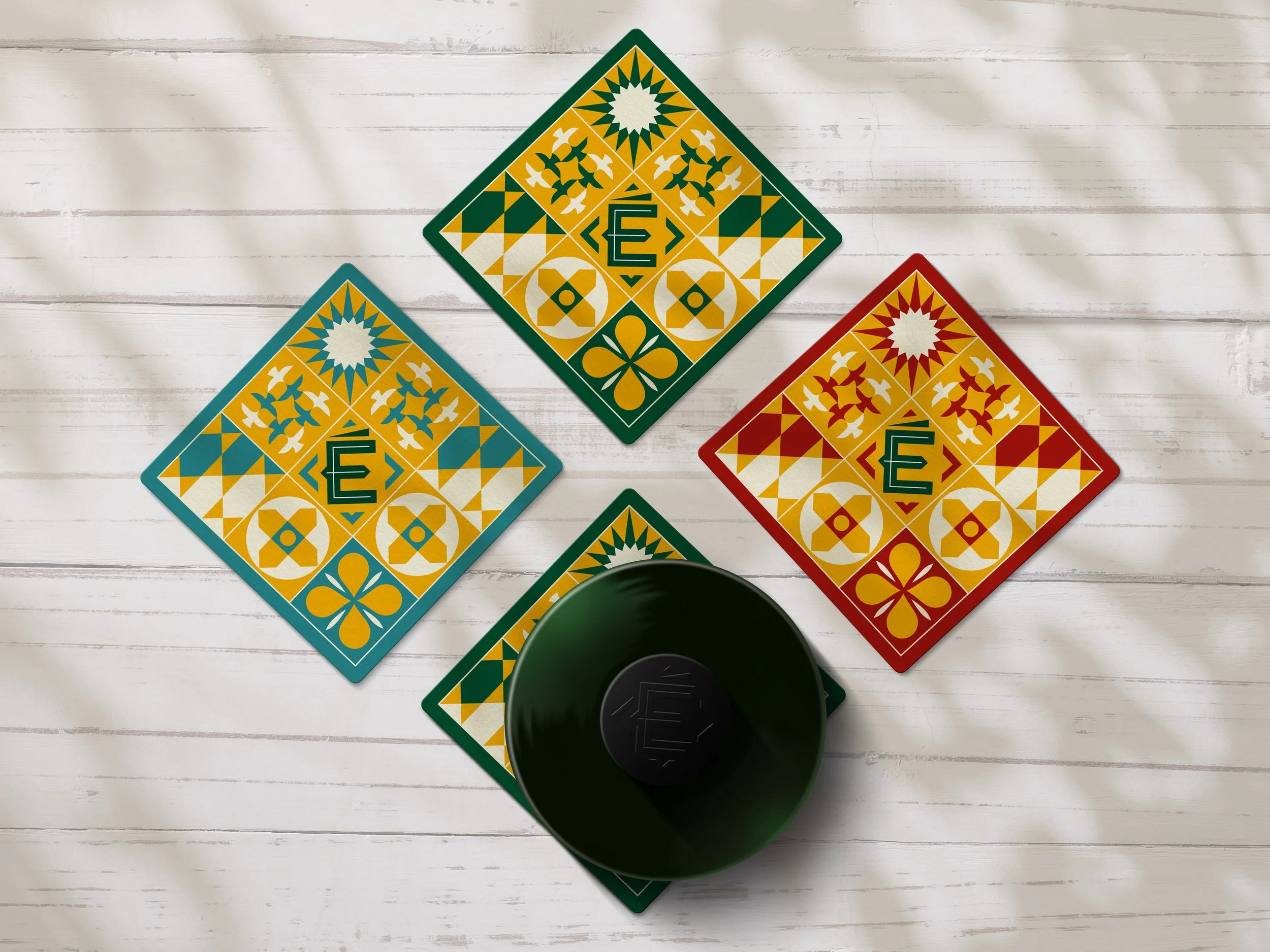 Promotional brand drip coaster for Ético Extra Virgin Olive Oil sat on a dappled sunlit wooden table with a bottle of the oil. Shot is top down.