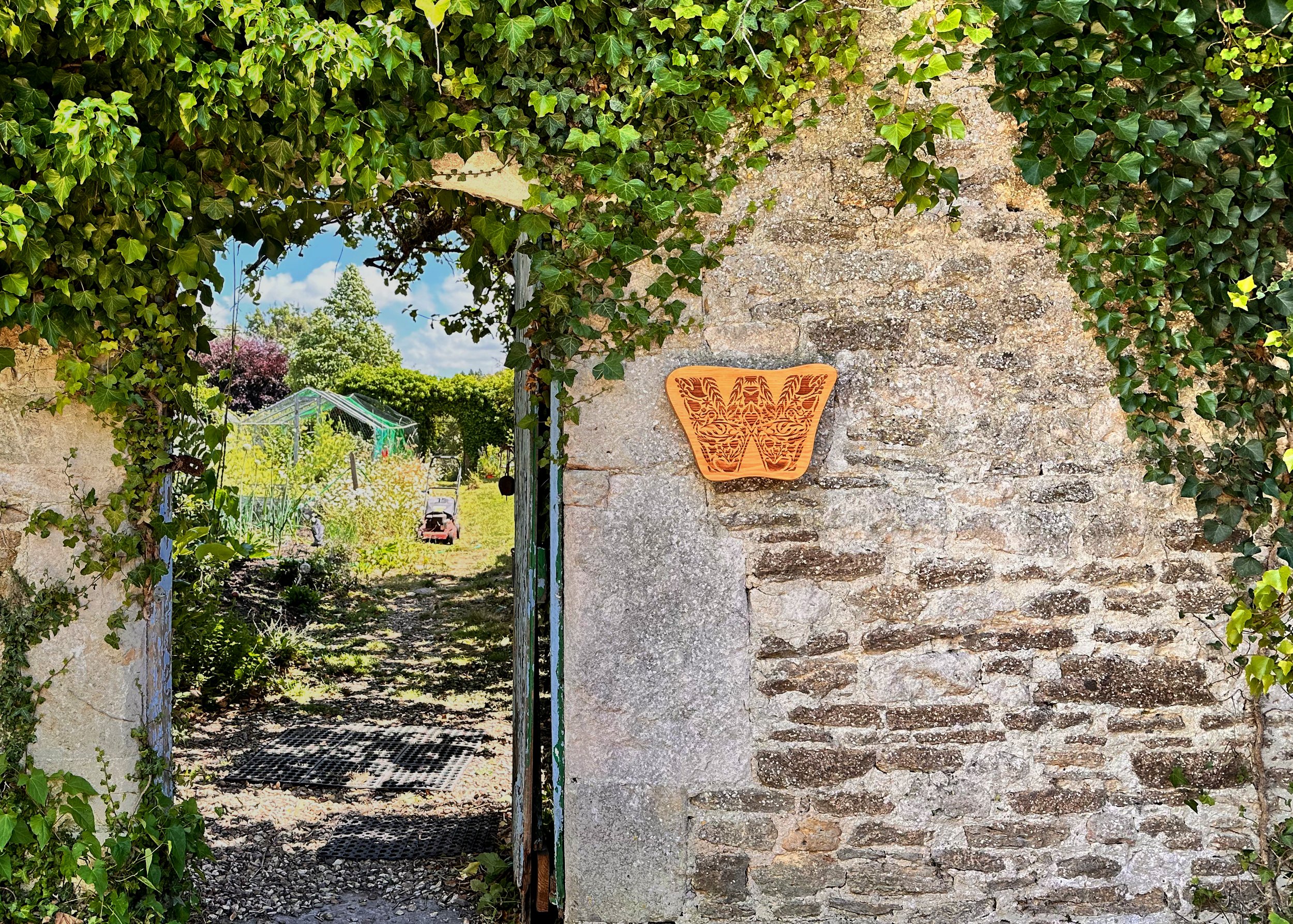 A wider shot showing the Withywood wooden sign on the wall next to the gate entrance to the garden. The sign purposely has no name as it’s not open to public - also giving it a mysterious feel.