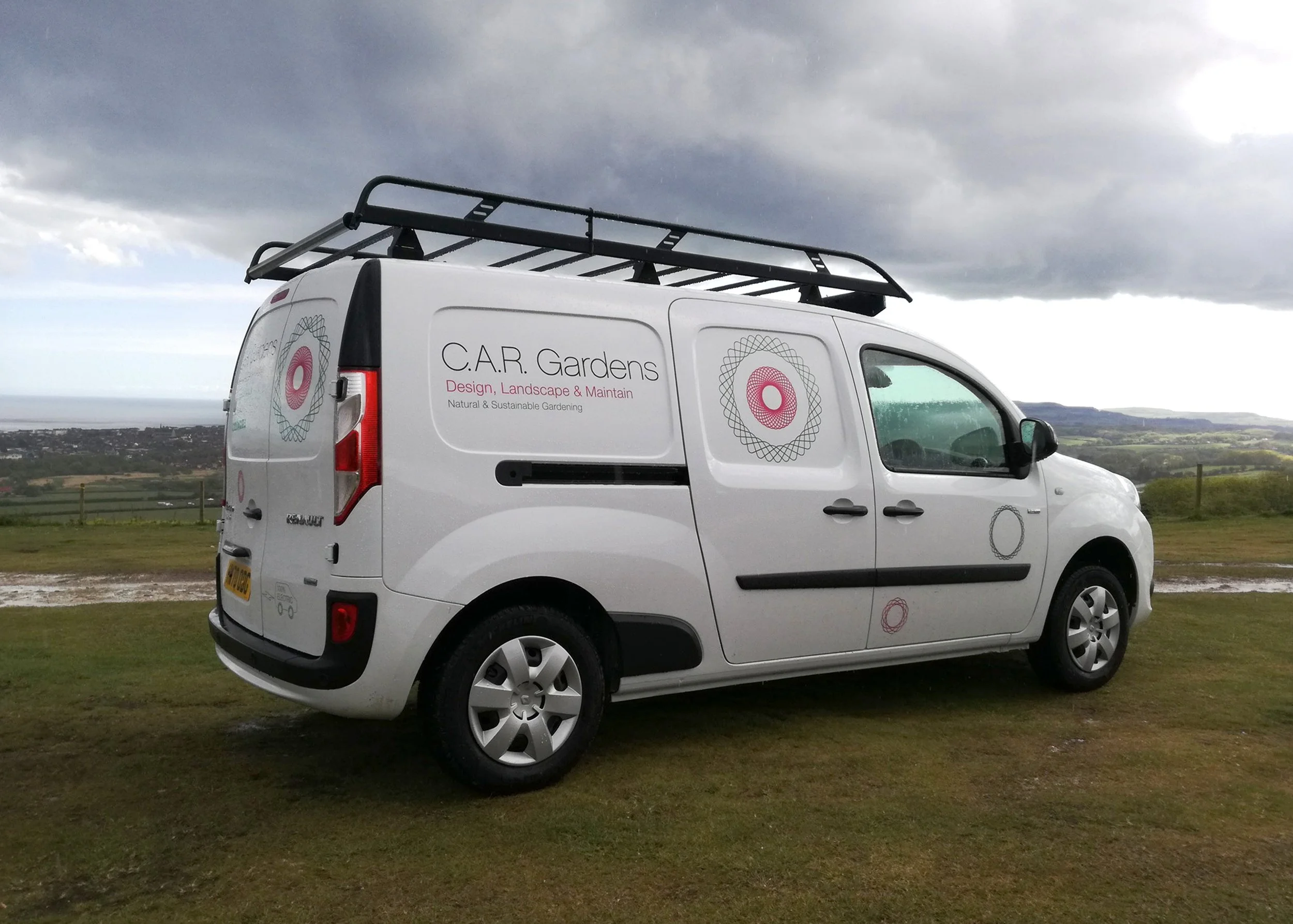 One of C.A.R. Garden’s 9 white vans displaying the brandmark and freeform spirograph artwork. This is also a 100% Electric van.