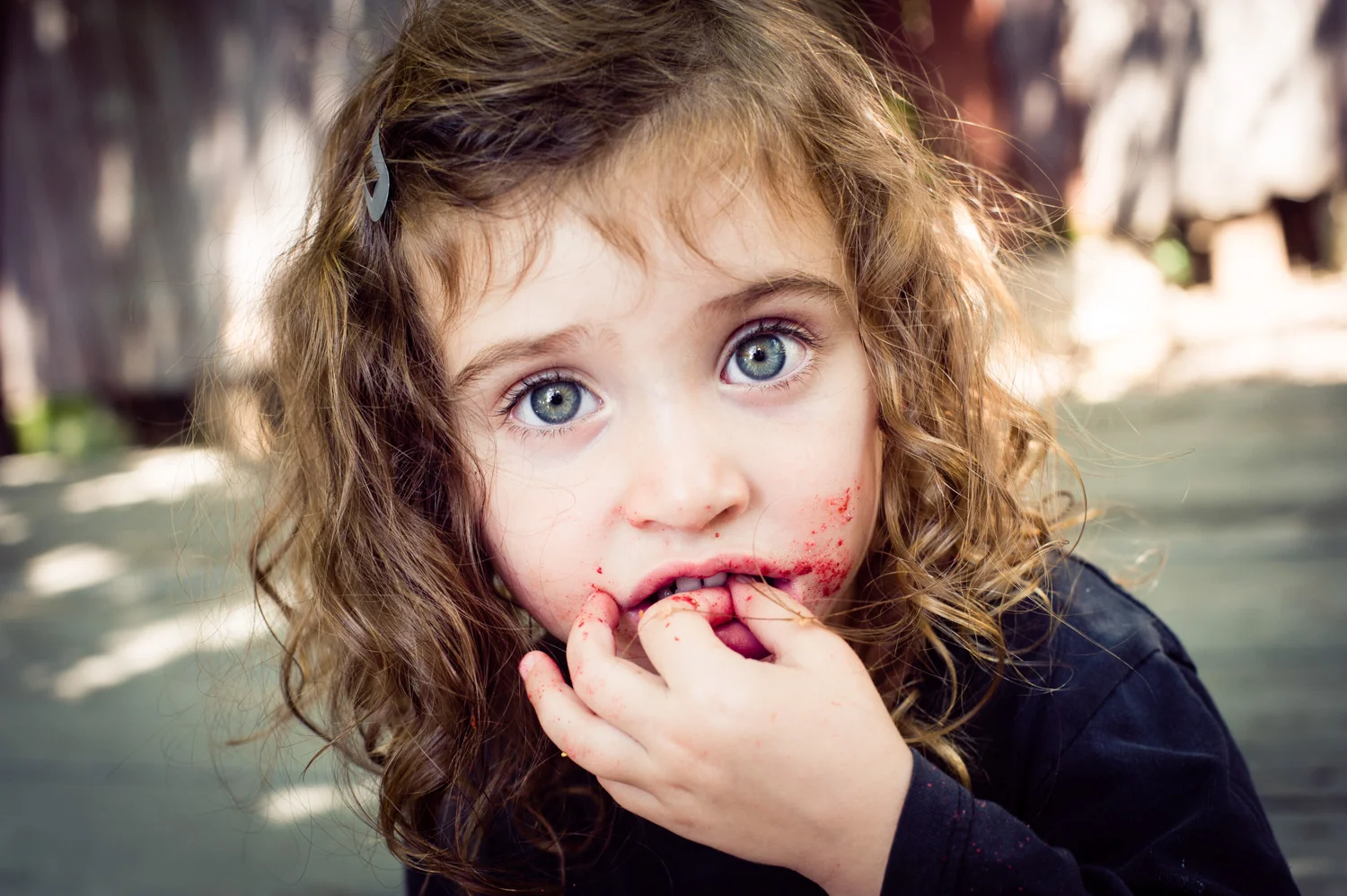 Little girl eating berries that stain her face.