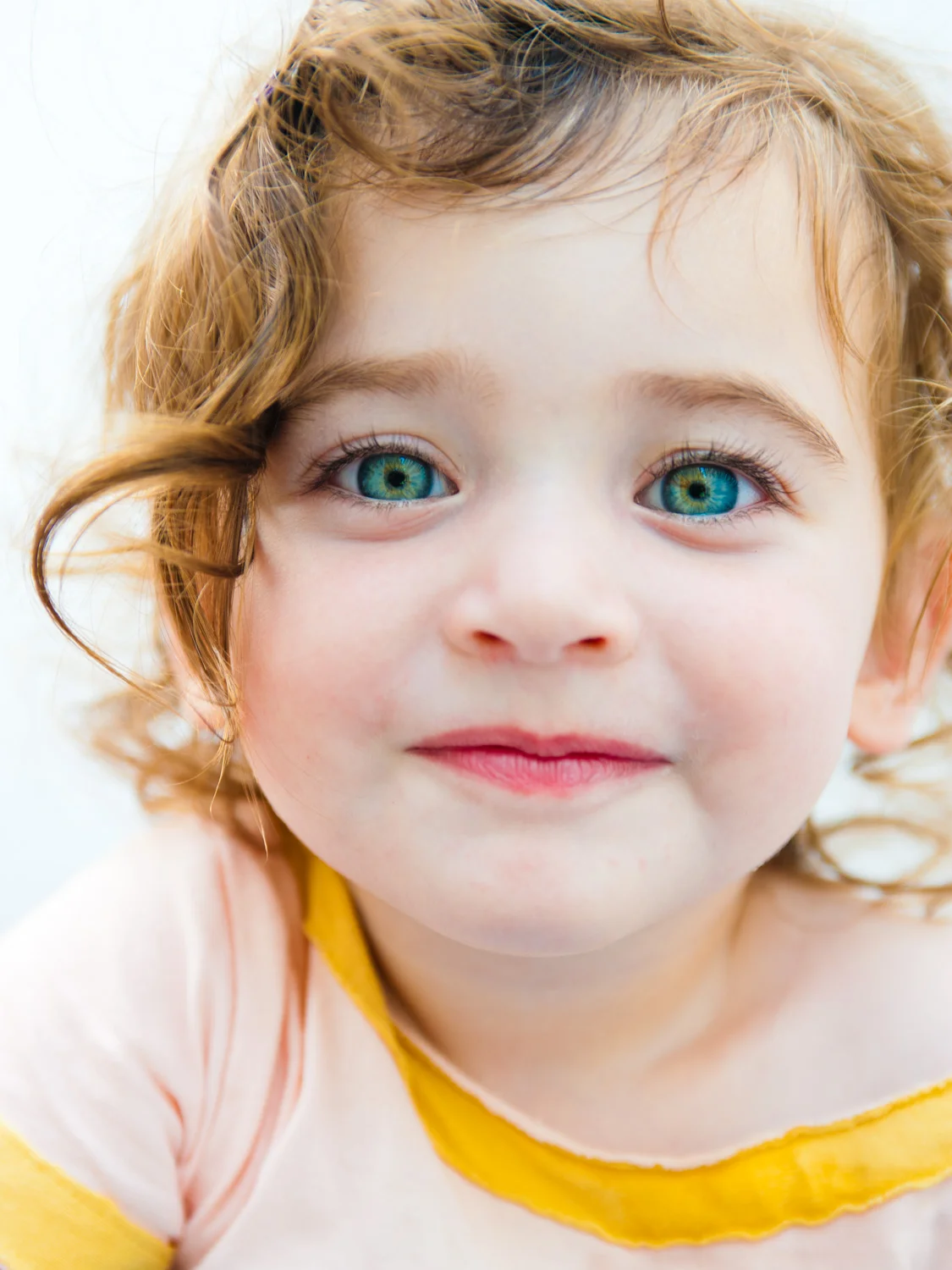 Close up of little girl with big blue-green eyes.