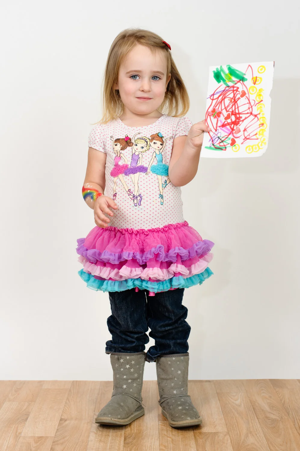 Girl holds her colorful drawing.